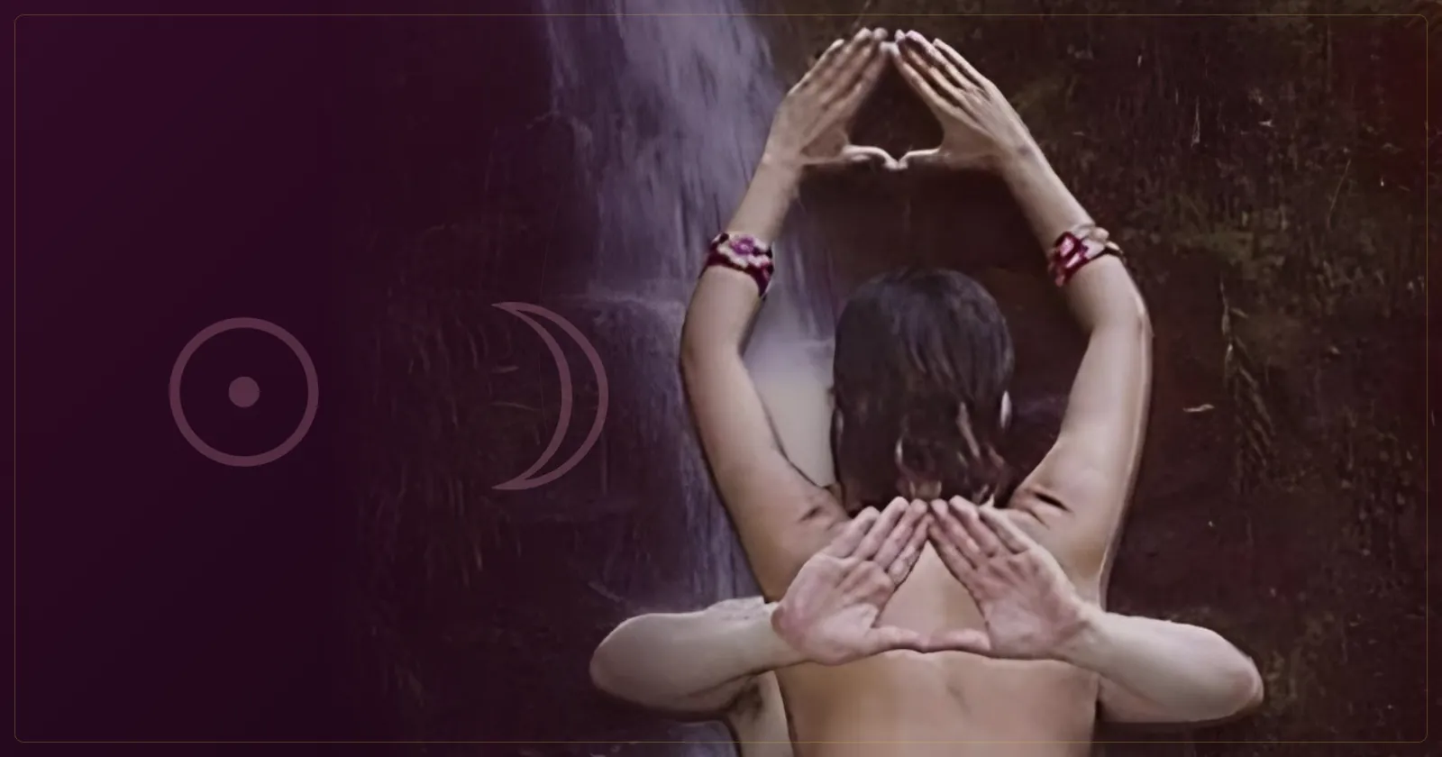 Casal sentado em abraço meditativo diante de uma cascata, com os braços erguidos e as mãos unidas em forma de triângulo