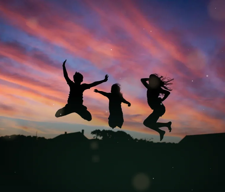 Três pessoas saltando de alegria ao pôr do sol