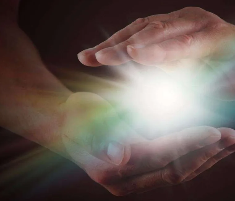 Mãos em imposição com luz entre elas
